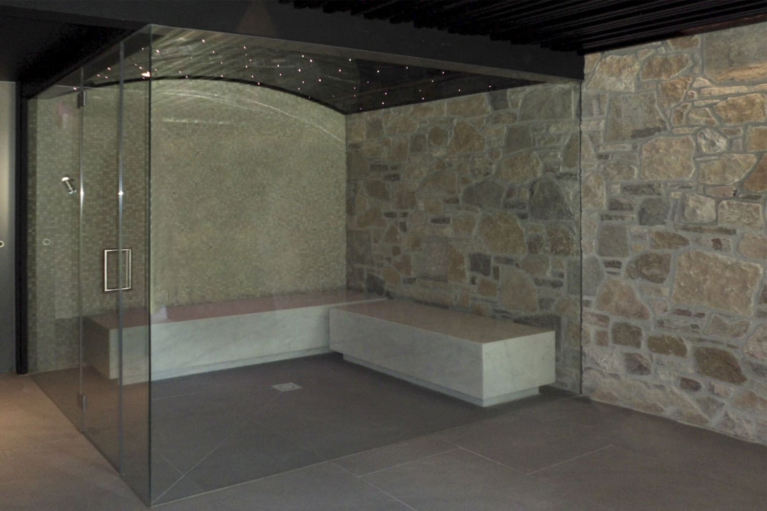 Baño turco o hammam de obra con cielo estrellado y exterior de cristal. 